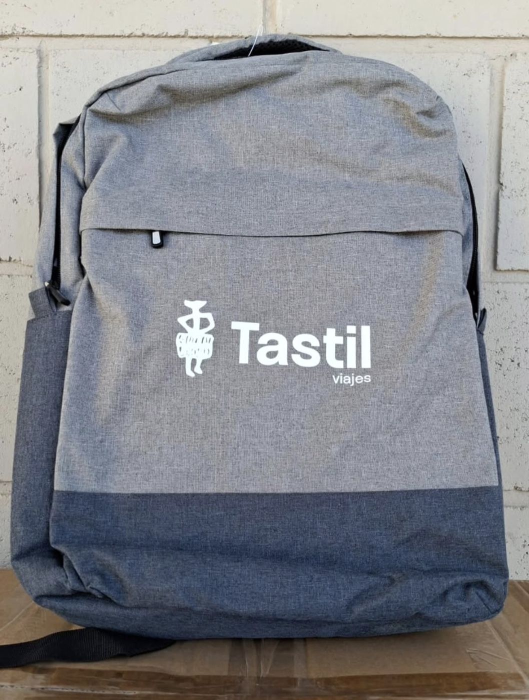 Mochila gris con logo de Tastil Viajes